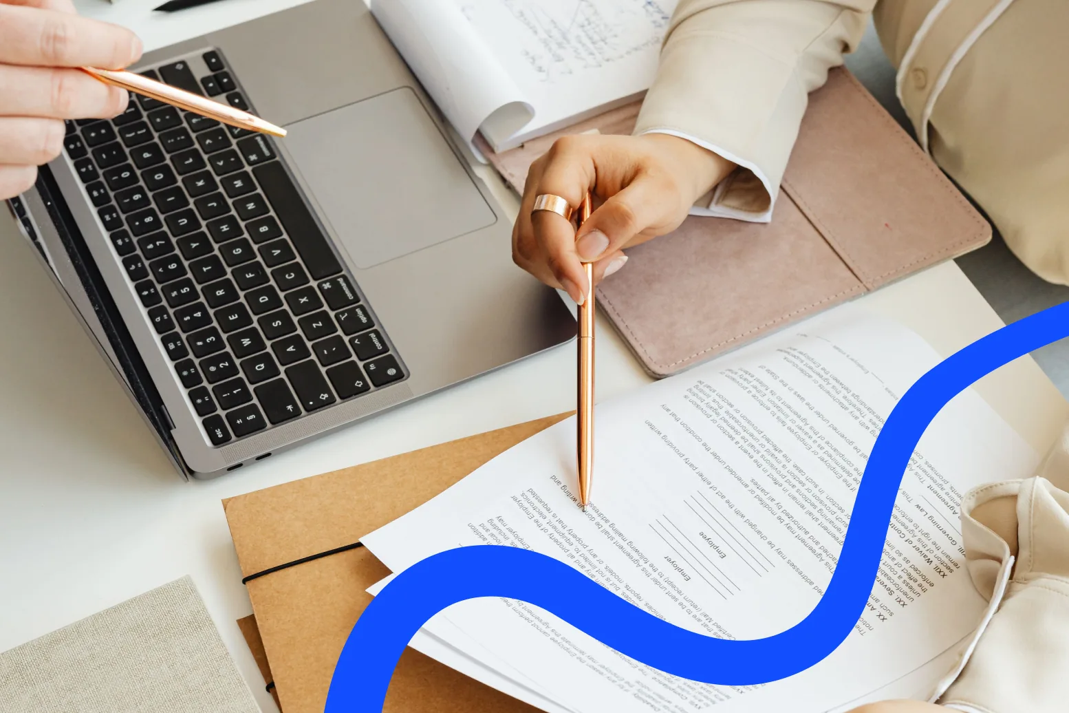 Two people reviewing a contract and paperwork at a desk with a laptop